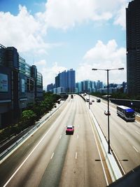 Vehicles on road in city against sky