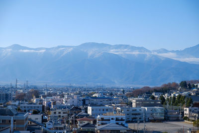 High angle view of townscape and mountains against blue sky