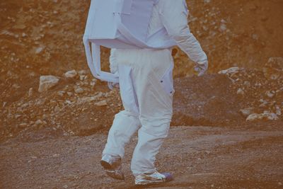 Low section of person wearing space suit walking on land