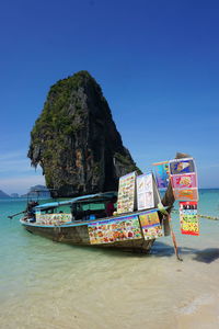 Boat moored on beach against clear blue sky