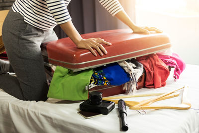 Midsection of woman packing luggage at home