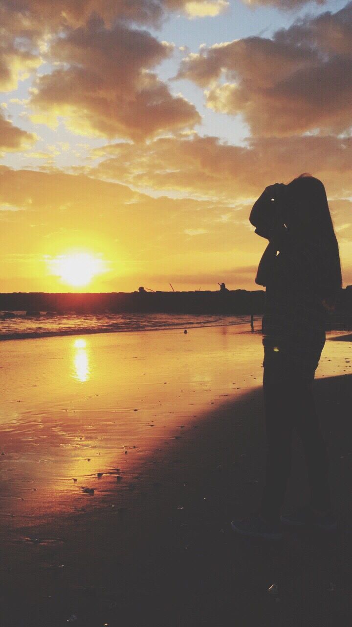 SILHOUETTE OF WOMAN STANDING ON BEACH