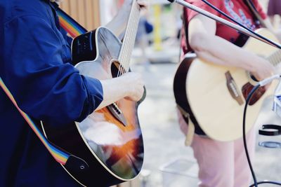 Midsection of street performers playing guitar outdoors