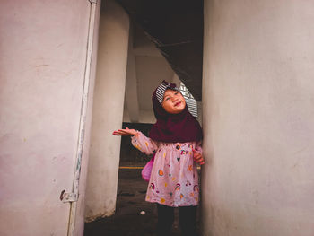 Portrait of young woman standing against wall