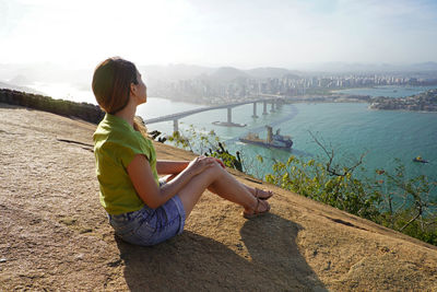 Beautiful woman sitting relaxed enjoying the breeze on top of mountain at sunset