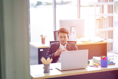 Young woman using phone while sitting on table