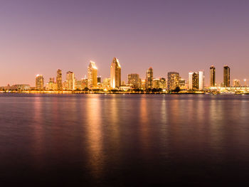 Illuminated buildings in city against clear sky