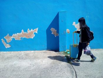 Full length of boy standing on blue wall