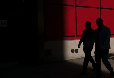 Silhouette man and woman walking on wall