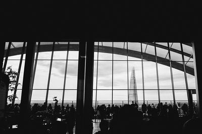 Silhouette people in city against sky seen through window