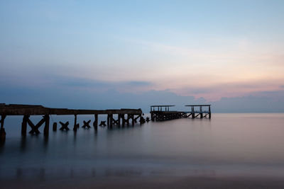 Pier on sea against sky during sunset