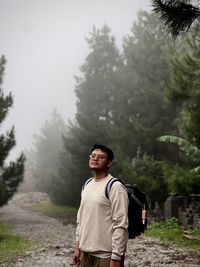 Portrait of young man standing against trees