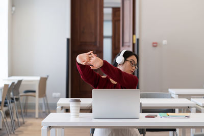 Young asian girl recreate during work on laptop in coworking space stretch arms to relief strain