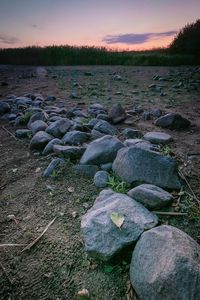 Rocks on field against sky during sunset