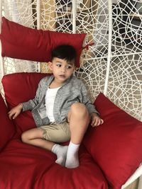 Cute boy sitting on sofa at home