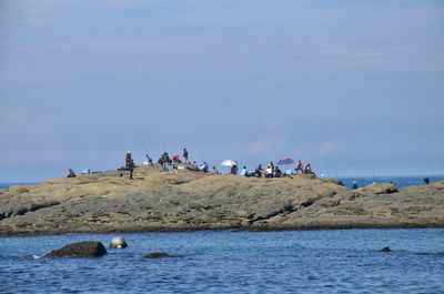 People gathered on huge rock amidst sea