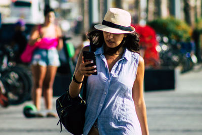 Midsection of woman holding mobile phone in city