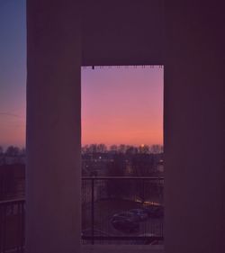 Silhouette buildings seen through window during sunset