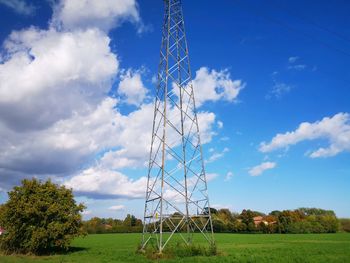 Low angle view of electricity pylon on field against sky