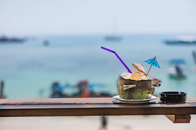 Close-up of drink on table against sea