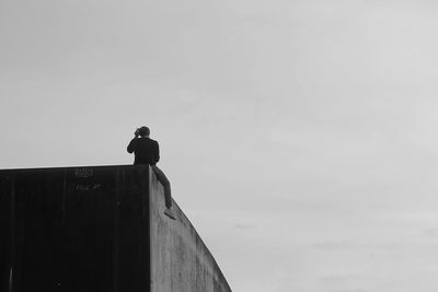 Low angle view of bird perching on building against sky