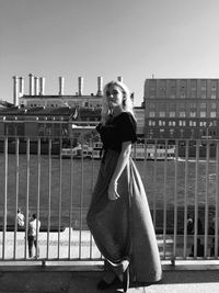 Full length of woman standing against railing in city