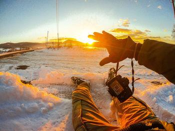 Shadow of man photographing on shore against sky during sunset