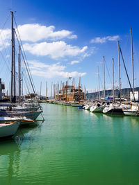 Sailboats moored at harbor against sky