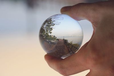 Close-up of man holding glass against sky