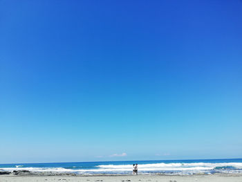 Scenic view of beach against clear blue sky