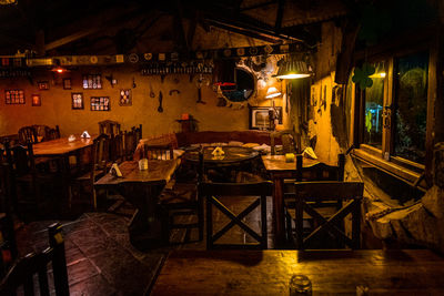 Empty chairs and tables at sidewalk cafe against buildings at night