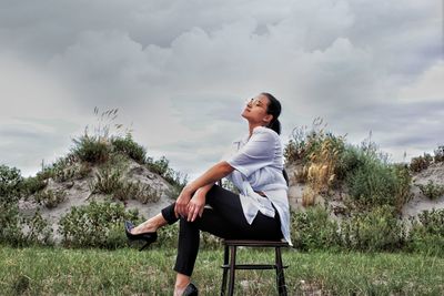 Full length of woman sitting on field against sky