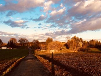 Road amidst field against sky