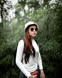 Portrait of young woman wearing sunglasses standing on field