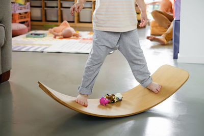 Child playing on balance board for toddlers in kids room. curvy rocker board used for motor physical