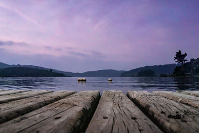 Pier over lake against sky during sunset