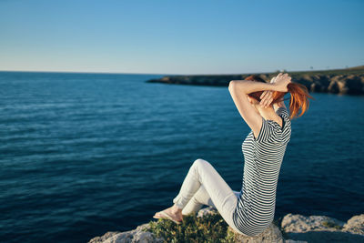 Woman sitting on rock near sea