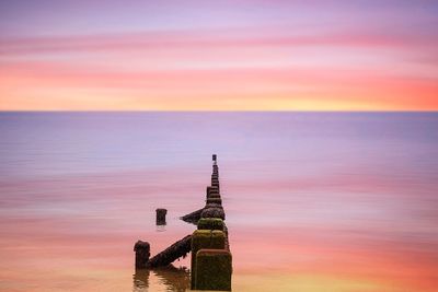 Scenic view of sea against cloudy sky at sunset