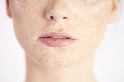 Midsection of woman with freckles on face against white background