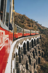 Toy train passing through an arched bridge in the countryside, from kalka to shimla.