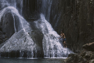 Man standing under waterfall