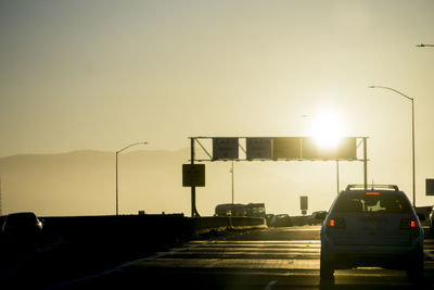 Cars on road against sky during sunset