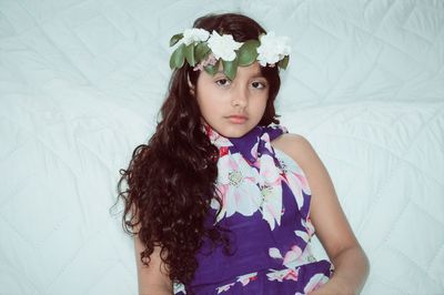 Portrait of girl wearing flowers while lying on bed at home