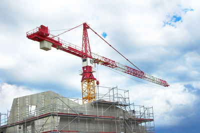 Low angle view of crane at construction site against sky