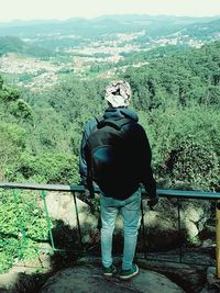 Rear view of man standing on mountain against sky