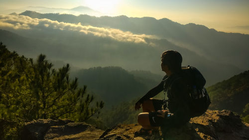 Man sitting on rock against mountains
