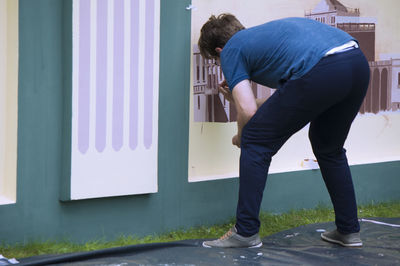 Rear view of man standing against wall in city