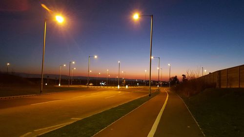 Illuminated road against sky at night