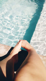 Low section of woman relaxing by swimming pool