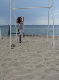 Young woman with hand in hair standing by lookout tower at sandy beach